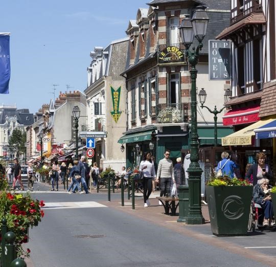 Une rue commerçante, des magasins, des enseignes et des promeneurs.